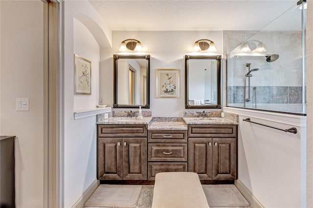 bathroom with a tile shower, vanity, and a textured ceiling