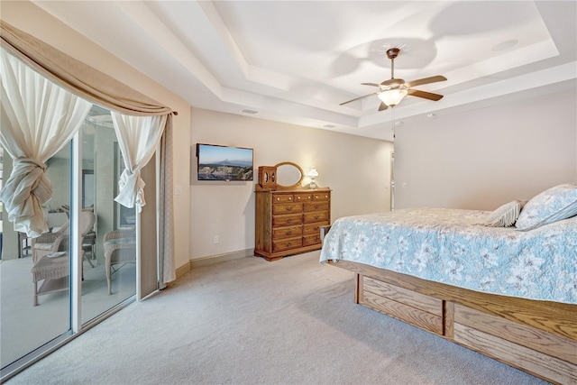 carpeted bedroom with access to exterior, a raised ceiling, and ceiling fan