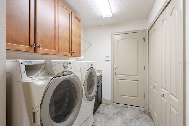 laundry area with cabinets, a textured ceiling, and washer and clothes dryer