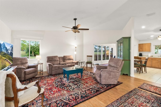 living room featuring vaulted ceiling, light hardwood / wood-style floors, and ceiling fan