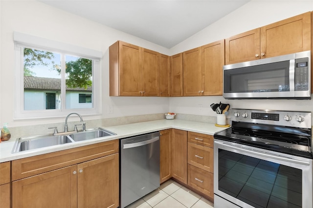 kitchen with stainless steel appliances, vaulted ceiling, sink, and light tile patterned floors