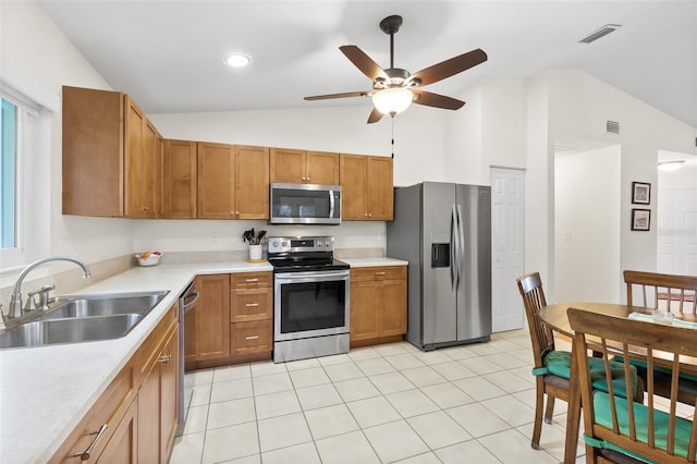 kitchen featuring lofted ceiling, sink, light tile patterned floors, appliances with stainless steel finishes, and ceiling fan