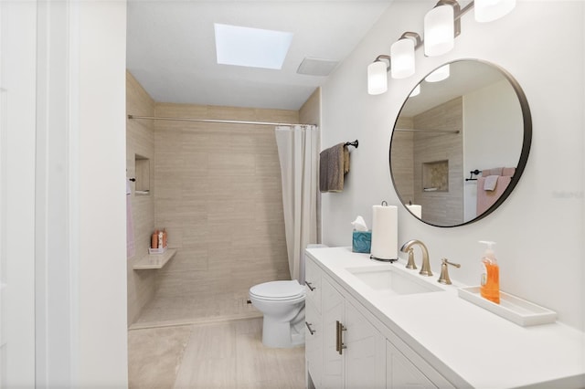 bathroom with tile patterned floors, toilet, a skylight, vanity, and curtained shower