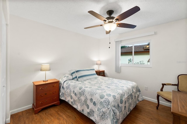 bedroom with dark hardwood / wood-style flooring, ceiling fan, and a textured ceiling