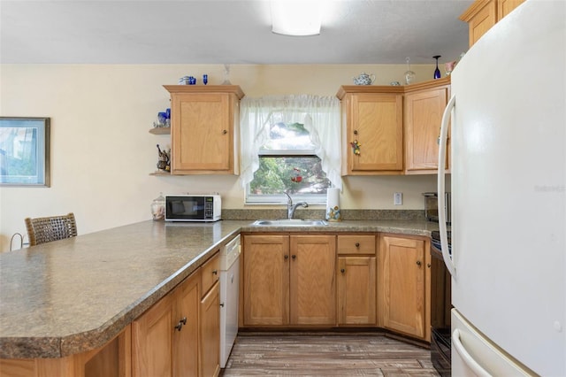 kitchen with sink, hardwood / wood-style floors, white appliances, and kitchen peninsula