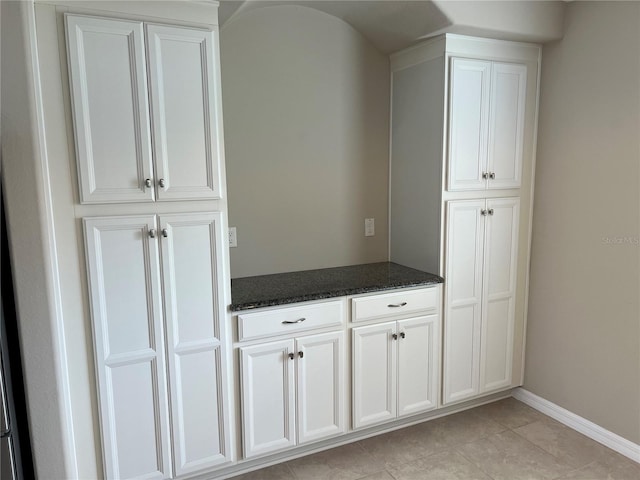 interior space with white cabinetry, dark stone countertops, and light tile patterned flooring