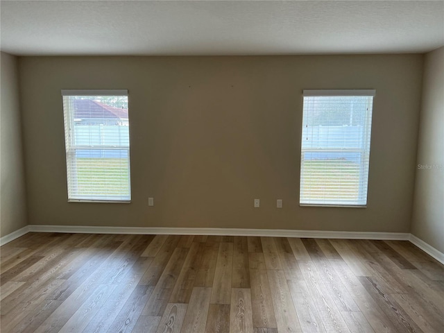 empty room with light hardwood / wood-style flooring and a textured ceiling