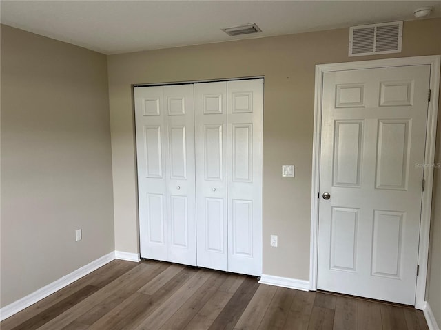 unfurnished bedroom with dark wood-type flooring and a closet