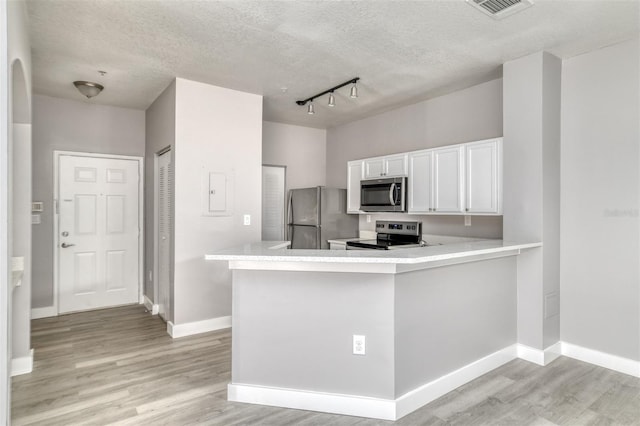 kitchen with white cabinetry, appliances with stainless steel finishes, light wood-type flooring, and kitchen peninsula