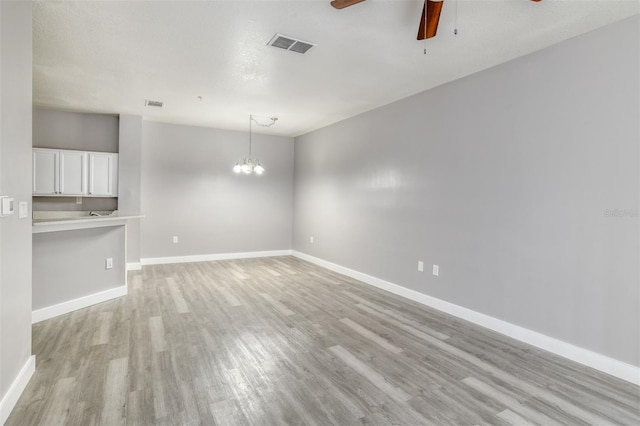 interior space with ceiling fan with notable chandelier, light hardwood / wood-style flooring, and a textured ceiling