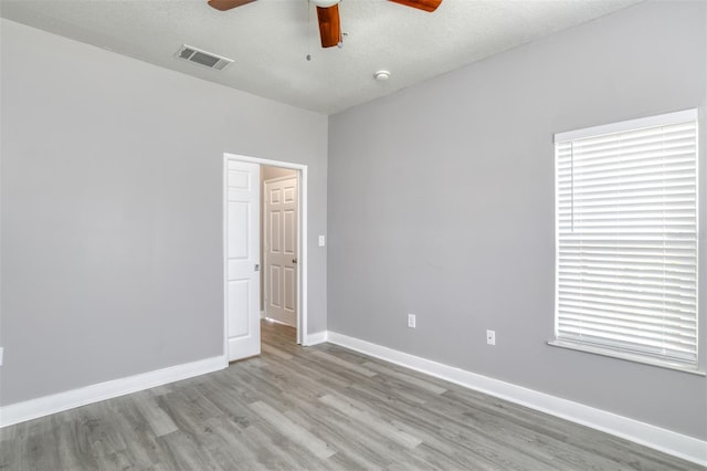 spare room with a textured ceiling, light hardwood / wood-style flooring, and ceiling fan