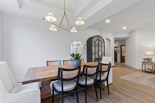 dining space featuring wood-type flooring, crown molding, and a tray ceiling