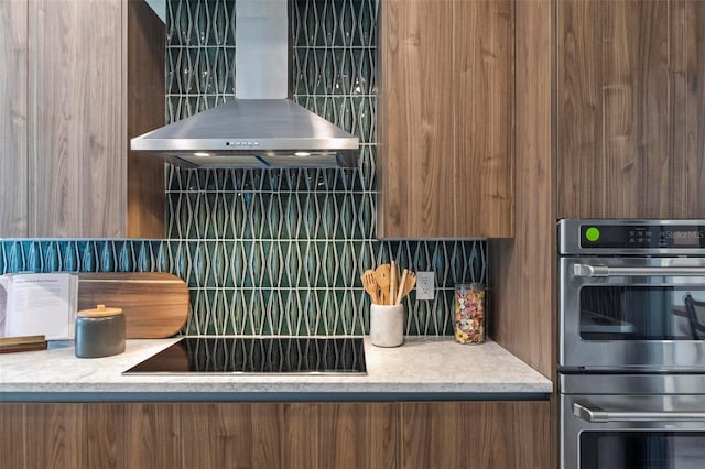 kitchen featuring black electric cooktop, double oven, decorative backsplash, and wall chimney exhaust hood