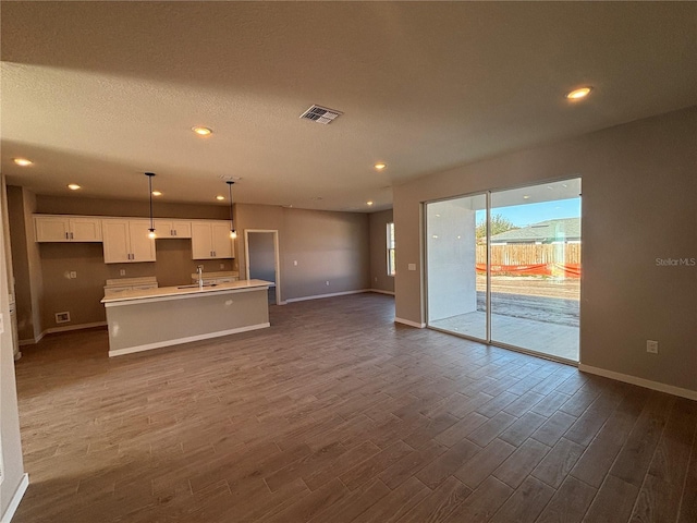 unfurnished living room with dark hardwood / wood-style flooring, sink, and a textured ceiling