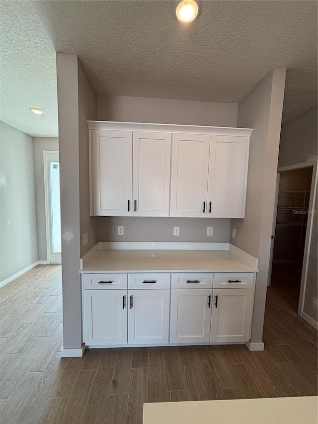 kitchen featuring hardwood / wood-style floors, white cabinets, and a textured ceiling