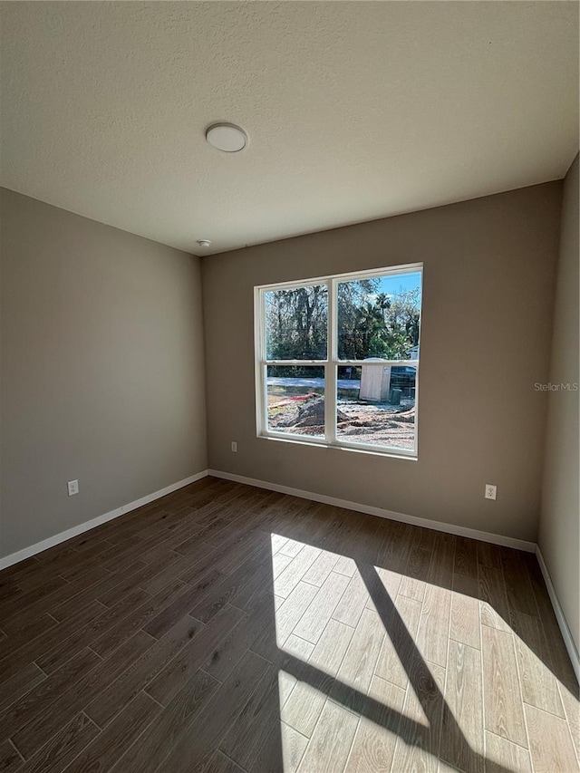 unfurnished room featuring dark hardwood / wood-style floors and a textured ceiling