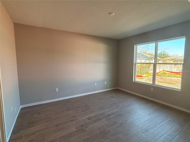 empty room with a textured ceiling and dark hardwood / wood-style flooring