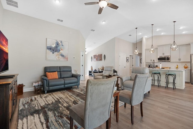 living room featuring sink, high vaulted ceiling, light hardwood / wood-style floors, and ceiling fan