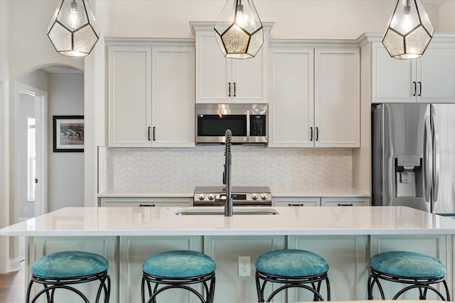 kitchen with stainless steel appliances, a kitchen island with sink, a breakfast bar area, and decorative light fixtures