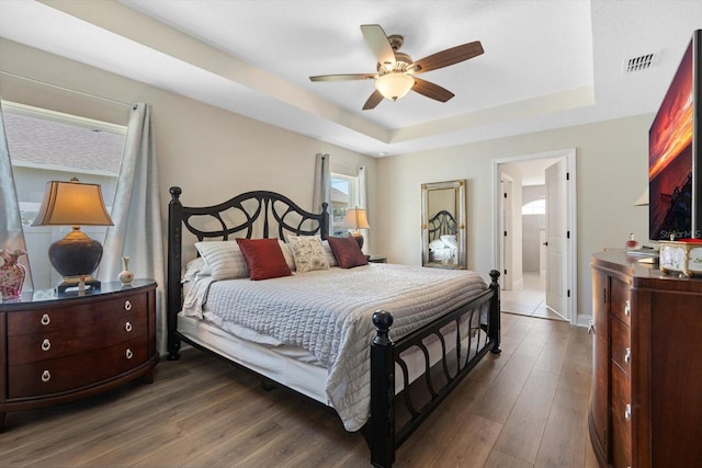 bedroom featuring dark wood-type flooring, ceiling fan, and a raised ceiling