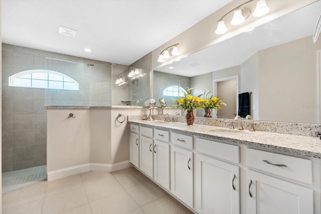 bathroom featuring tile patterned flooring, vanity, a healthy amount of sunlight, and a tile shower