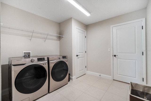 laundry area with washer and dryer and light tile patterned floors