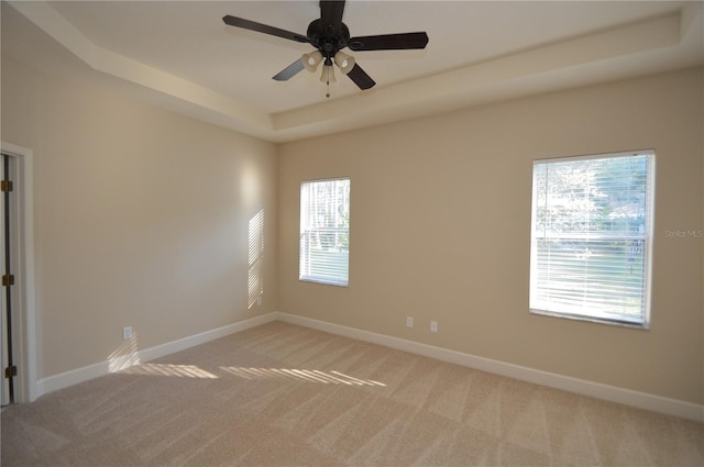 unfurnished room with light colored carpet, a raised ceiling, and ceiling fan