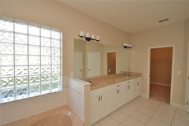 bathroom with a tub to relax in, tile patterned floors, and vanity