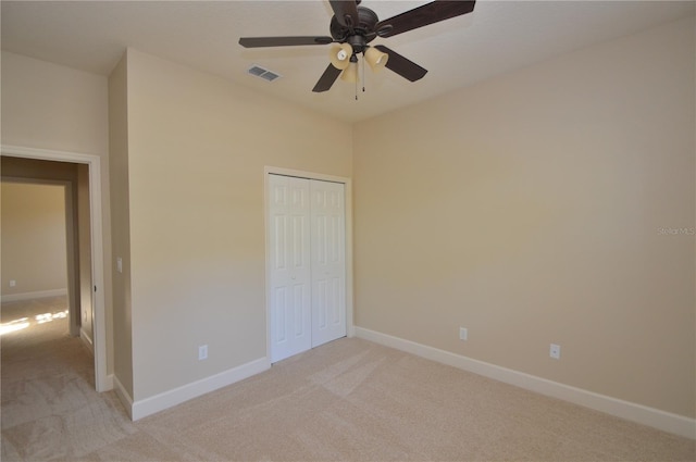 unfurnished bedroom featuring light carpet, ceiling fan, and a closet