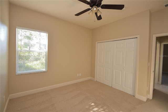 unfurnished bedroom featuring light colored carpet, ceiling fan, and a closet