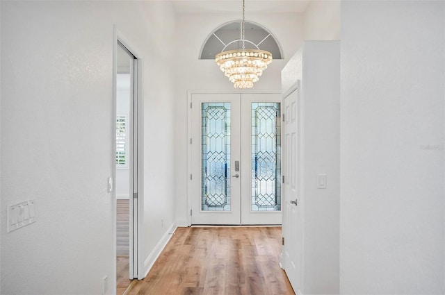 foyer featuring french doors, light hardwood / wood-style floors, and a notable chandelier