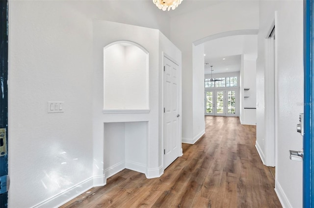 hall with hardwood / wood-style flooring, an inviting chandelier, and french doors