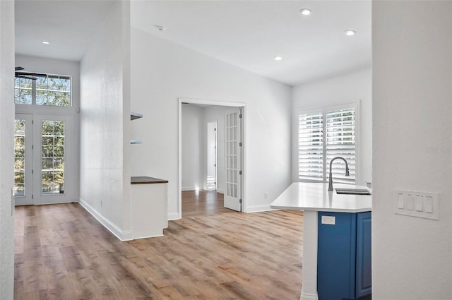 kitchen with blue cabinets, sink, a breakfast bar area, and light wood-type flooring