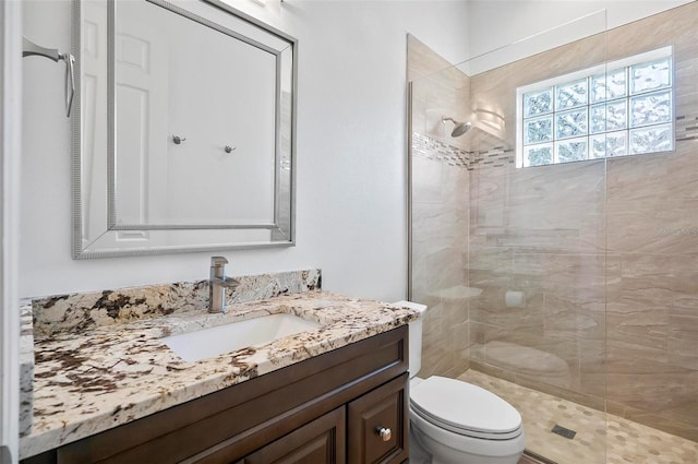 bathroom with vanity, toilet, and tiled shower