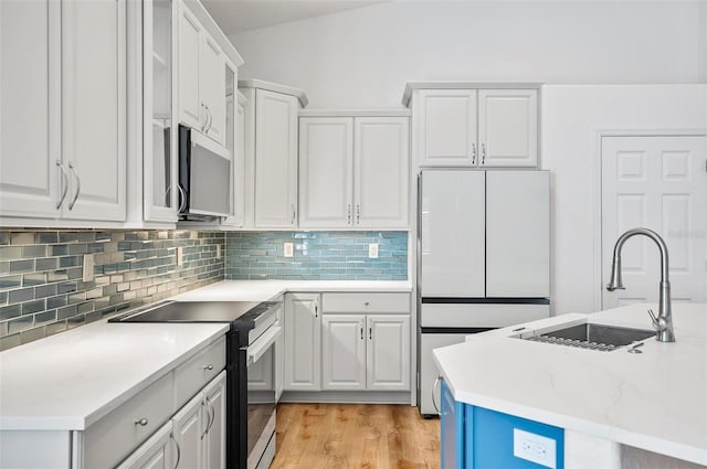 kitchen with white refrigerator, white cabinetry, sink, and black range with electric cooktop