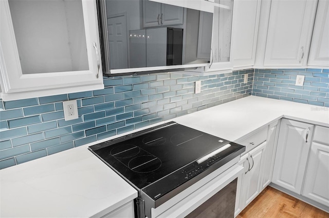 kitchen featuring white cabinetry, stainless steel electric stove, light hardwood / wood-style floors, and tasteful backsplash