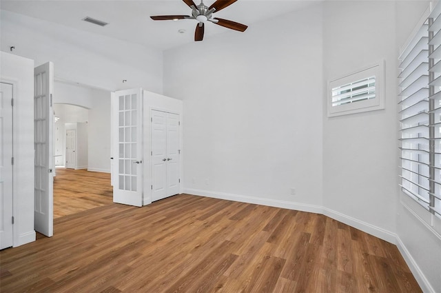 spare room with ceiling fan, wood-type flooring, and a high ceiling