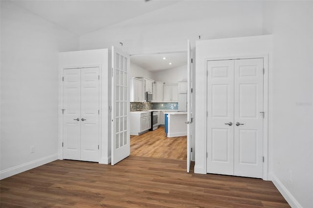 kitchen with white cabinetry, appliances with stainless steel finishes, dark hardwood / wood-style floors, and tasteful backsplash