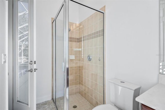 bathroom featuring vanity, a shower with door, and toilet