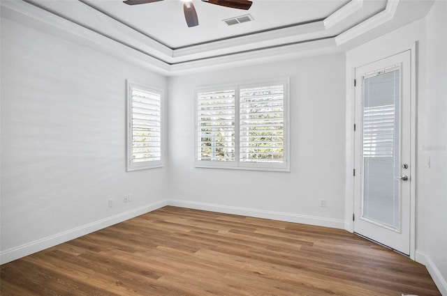 empty room featuring a raised ceiling, ornamental molding, hardwood / wood-style floors, and ceiling fan