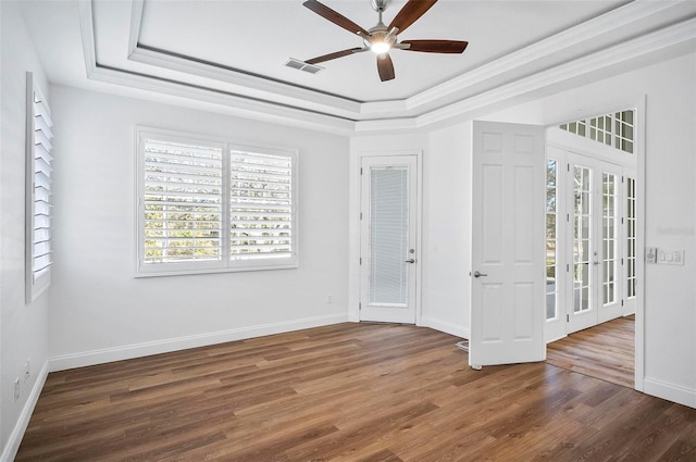 spare room with crown molding, dark wood-type flooring, a raised ceiling, and ceiling fan