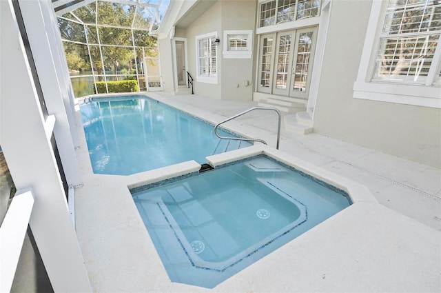 view of swimming pool featuring an in ground hot tub, glass enclosure, and a patio