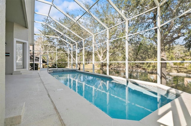 view of pool featuring a water view, glass enclosure, and a patio area