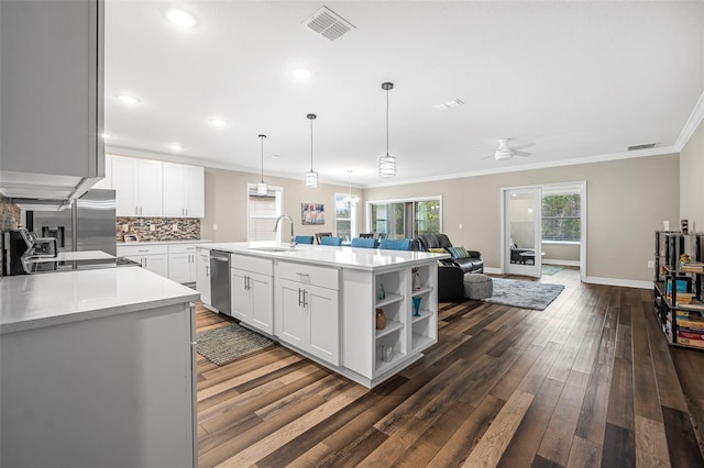 kitchen with dark wood-type flooring, white cabinetry, crown molding, a center island with sink, and appliances with stainless steel finishes