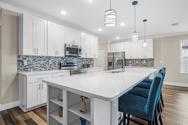 kitchen featuring white cabinetry, hanging light fixtures, a center island with sink, and appliances with stainless steel finishes