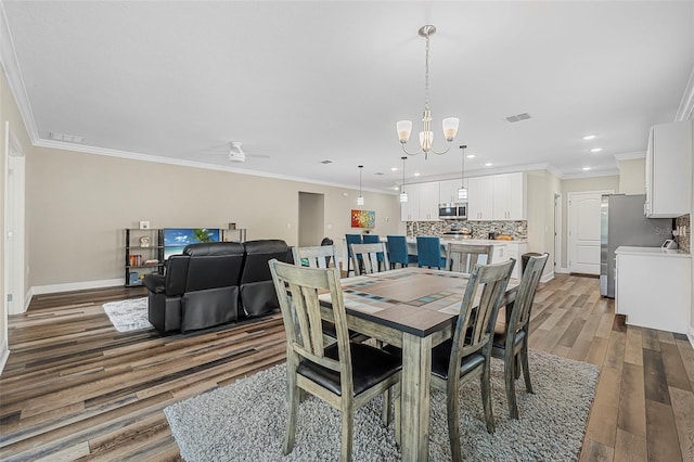 dining room featuring ceiling fan with notable chandelier, ornamental molding, and dark hardwood / wood-style floors