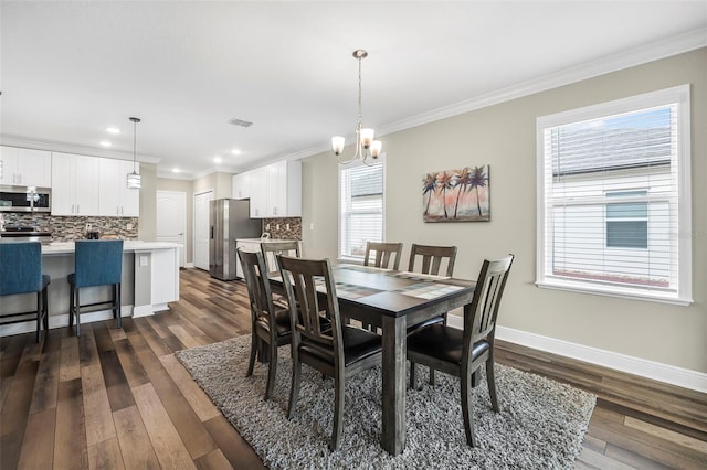 dining area with dark wood-type flooring, ornamental molding, and a chandelier