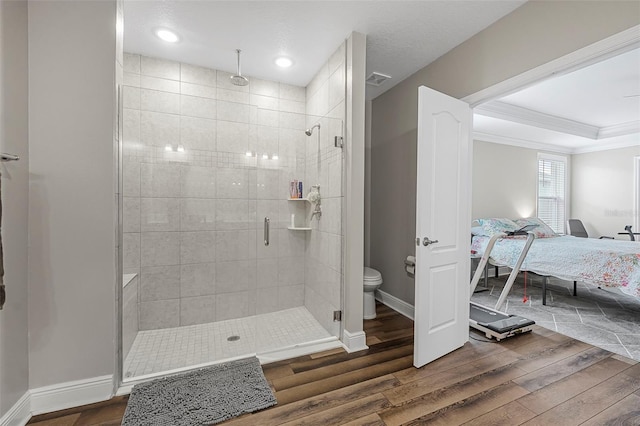 bathroom with crown molding, hardwood / wood-style flooring, a shower with shower door, and toilet