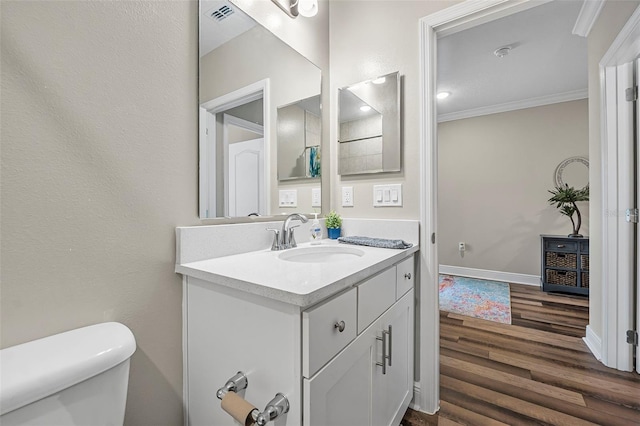 bathroom featuring vanity, hardwood / wood-style floors, ornamental molding, and toilet