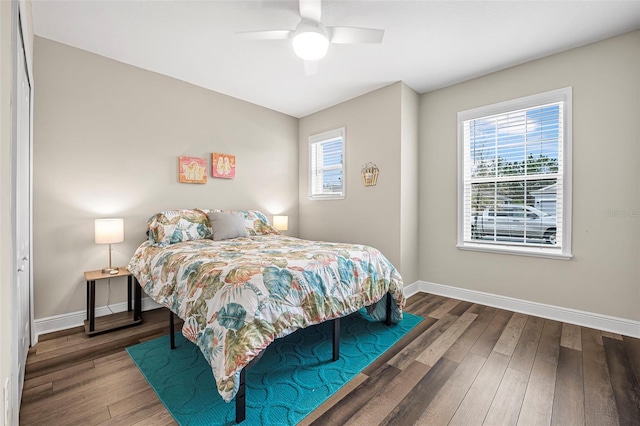 bedroom with multiple windows, dark hardwood / wood-style flooring, and ceiling fan